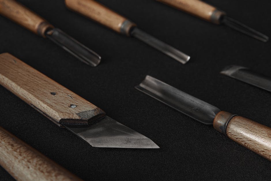 A detailed close-up of various woodworking tools with wooden handles on a black surface.