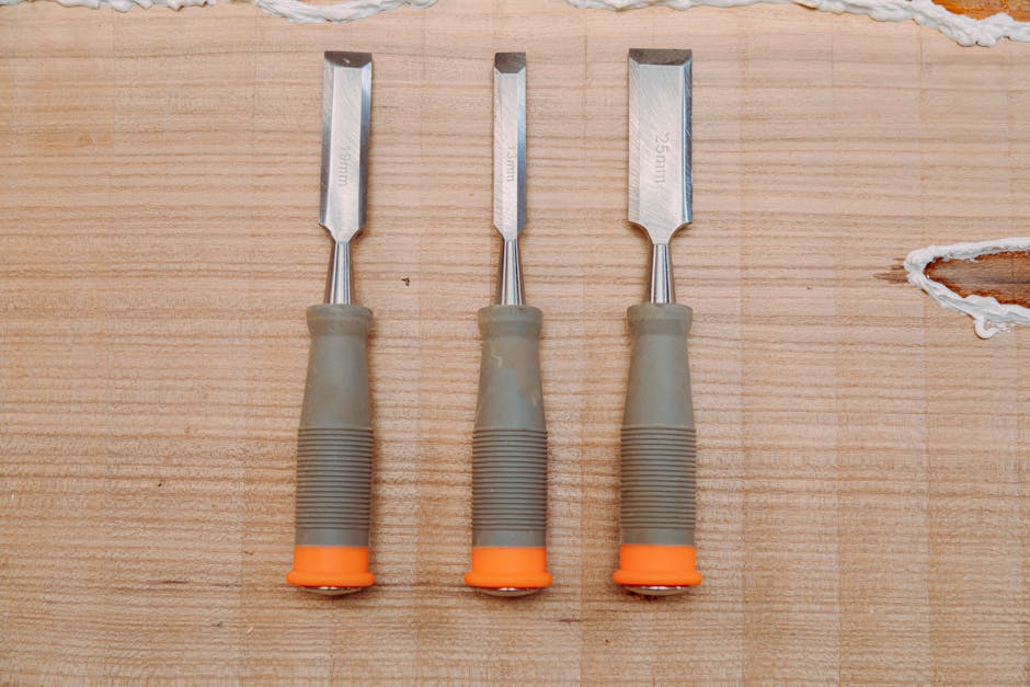 A flat lay of three metal chisels on a wooden surface, perfect for woodworking tools stock image.