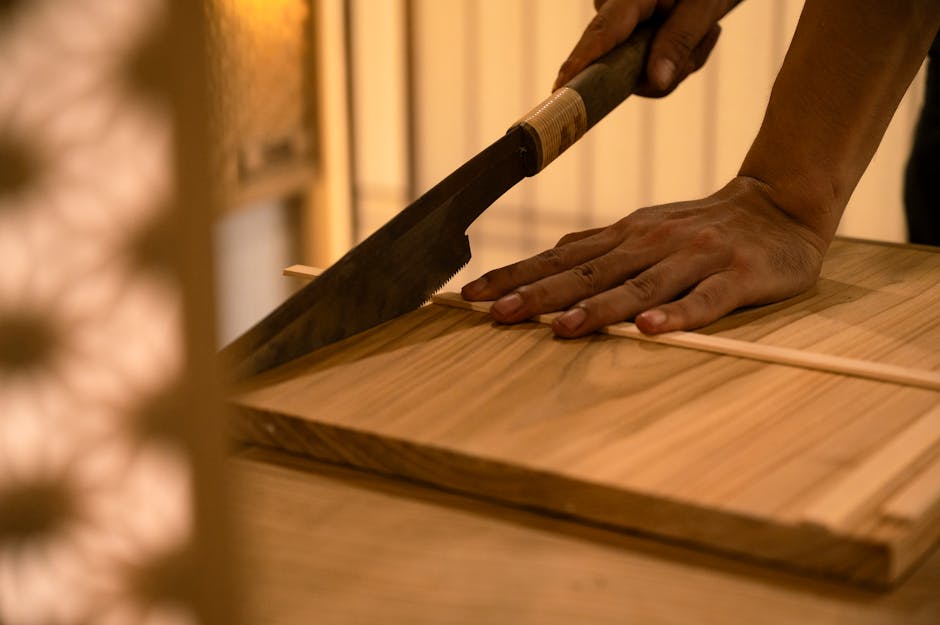 Close-up of a hand using a traditional saw to cut wood precisely. Perfect for woodworking themes.