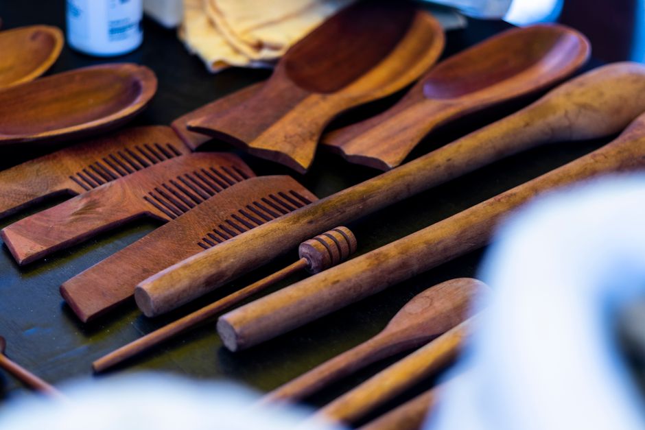 Close-up of handcrafted wooden kitchen utensils and combs arranged on a table, highlighting artisan craftsmanship.