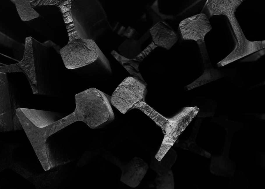 Dramatic black and white close-up of steel railroad track beams, highlighting texture and form.